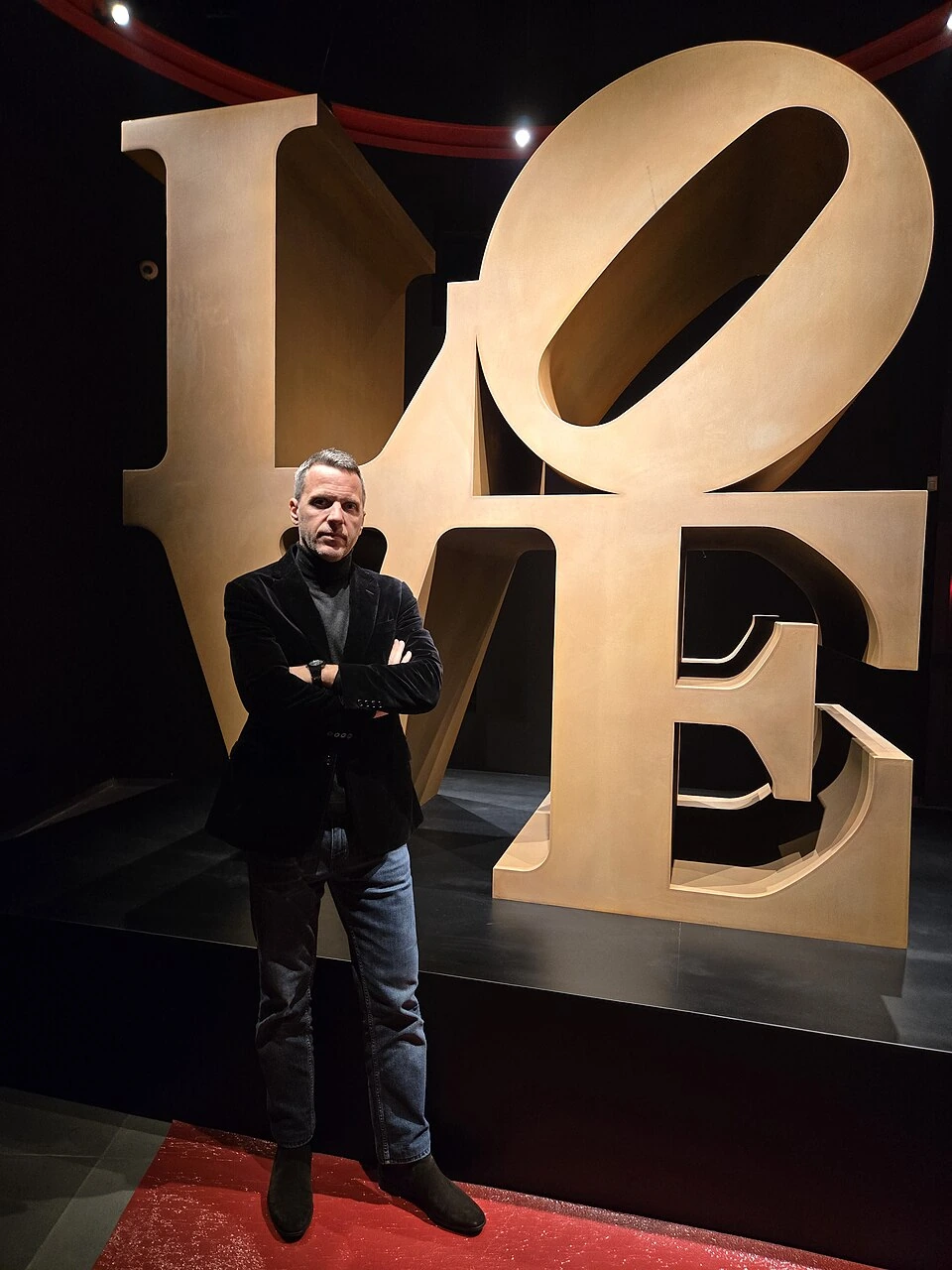 Evangelos Pistiolis standing indoors in front of large decorative letters